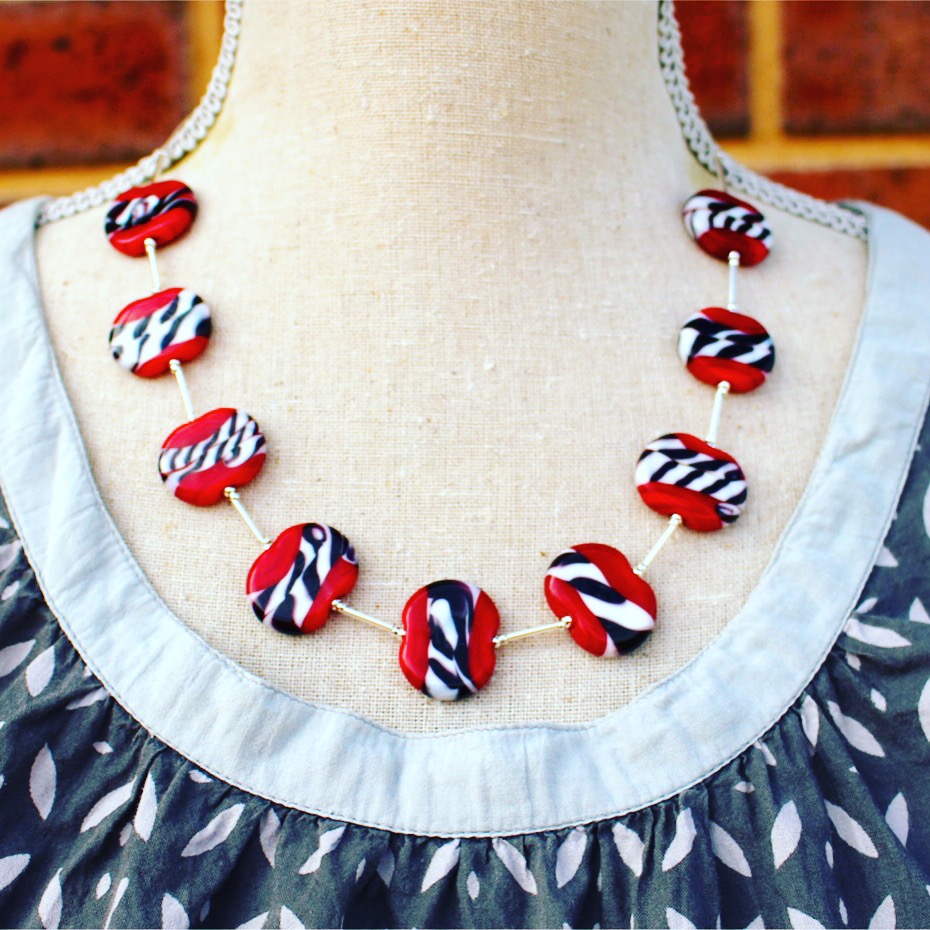 Brighten up a neutral dress with this stunning red white and black necklace by Julie Frahm